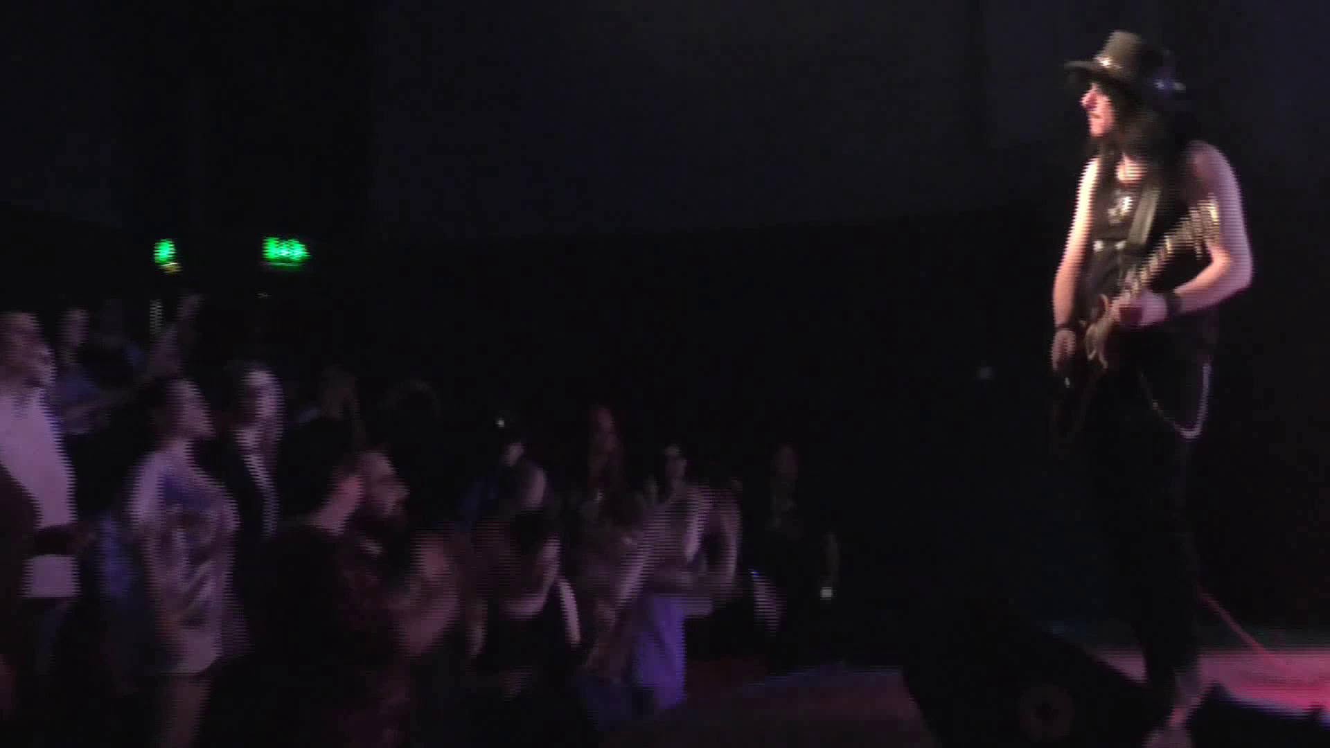 Paul McHugh on stage with an electric guitar and hat, in front of a crowd